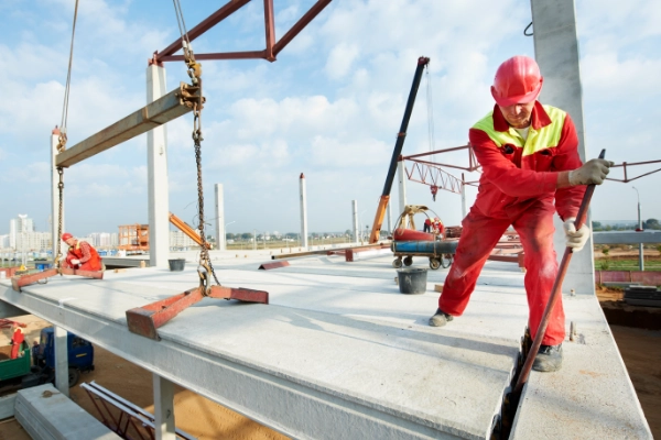Construction worker in a hard hat laying the foundation for a building.
