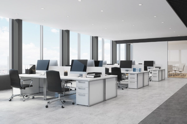 Empty office desks by the window in a high-rise building.